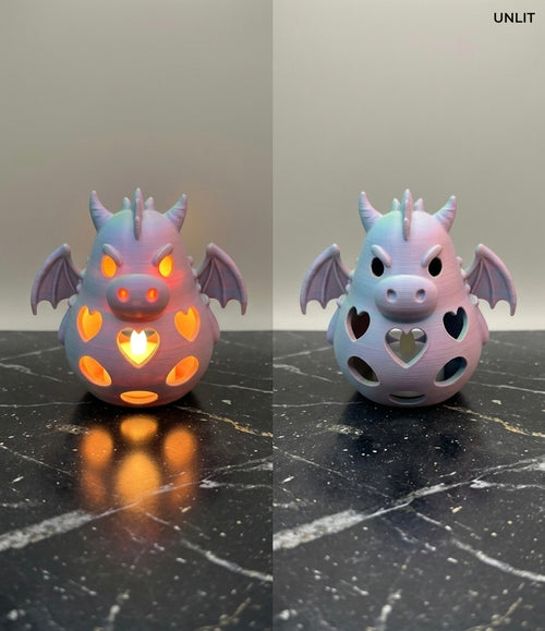 Side by side view of a 3D printed pastel dragon tealight holder showing it lit with a warm glow and unlit on a dark marble surface